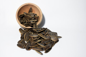 Sunflower seeds in a wooden bowl on a white background