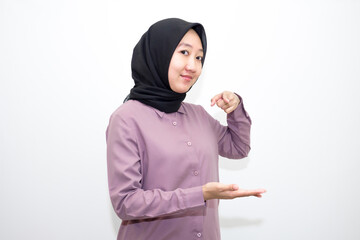 portrait of Indonesian Asian woman wearing shirt and hijab pointing with one and two hands to right, left and front. pointing to empty direction for advertising space.. Isolated on white background