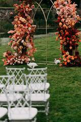 In a beautiful setting, a row of elegant white chairs has been meticulously arranged in front of a...