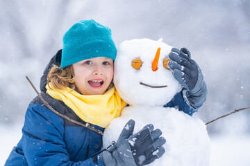 Fun Kid in winter park on a snowy cold winter day. Cute child playing with snow in winter. Portrait...