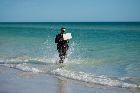 Excited businessman in wet suit run in sea. Funny business man, crazy comic business concept. Remote online working. Crazy summer business. Fun business lifestyle. Funny freelance businessman.