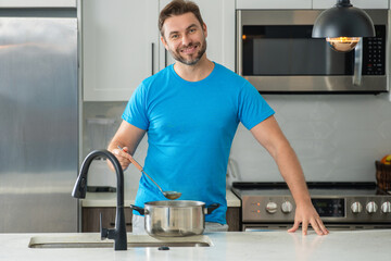 Man cooking at kitchen. Handsome man preparing delicious meal in modepn kitchen. Male chef cooking in kitchen. Millennial man preparing a healthy meal on kitchen home background. Kitchens utensils.
