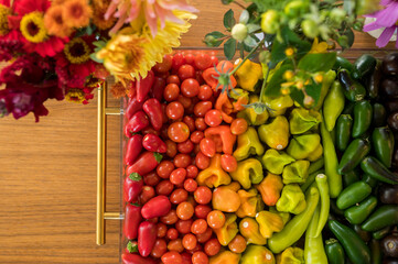 Colorful vegetables and flowers arranged in rainbow hues on wood table