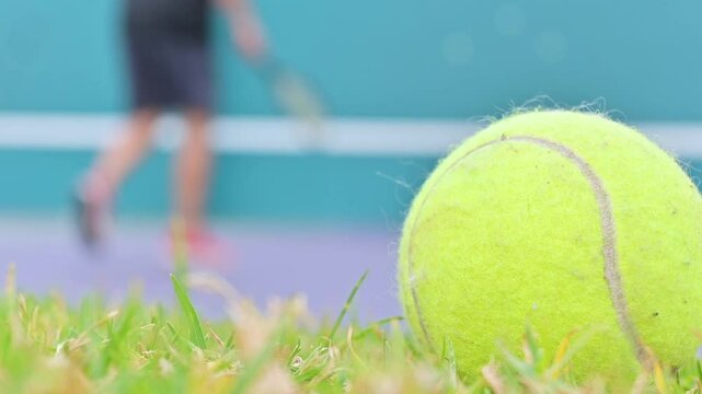 Close up of tennis ball and man practicing tennis outdoors