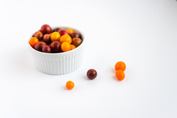 Bowl of colorful cherry tomatoes on a white background,fresh produce.