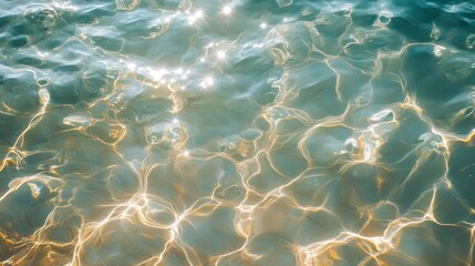 A top-down view of crystal-clear sea water surface with the sun reflecting off the gentle waves.