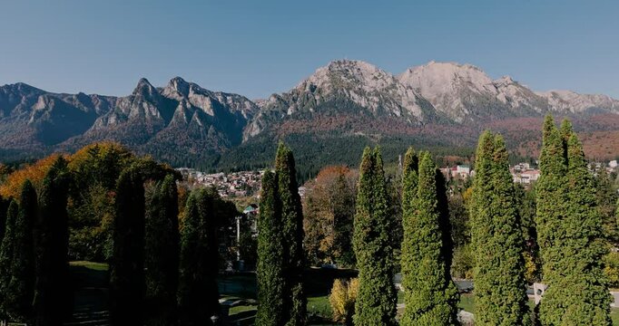 The Bucegi Mountains and Caraiman Peak in the background and Busteni city during a sunny autumn day.