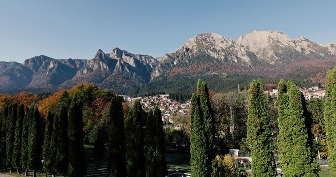 The Bucegi Mountains and Caraiman Peak in the background and Busteni city during a sunny autumn day.