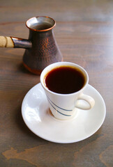 Cup of Hot Turkish Coffee with a Coffee Boiler Served on Wooden Table