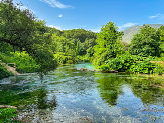 Unique water spring and natural phenomenon Blue Eye (Syri i Kalter) in Muzine, Albania. Bottomless crystal-clear blue lake surrounded by lush greenery and mountains. Peaceful enchanting atmosphere