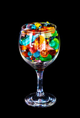 a wine glass full of miniature resin bottles of alcohol without labels with black bacground, focus in front