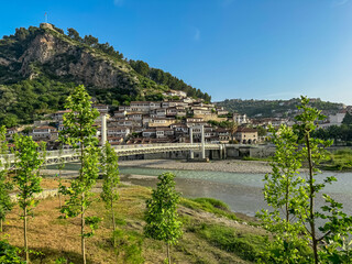 Panoramic view of footbridge Gorica over river Osum leading to Berat castle on hilltop in Albania. UNESCO World Heritage Site with well-preserved Ottoman-era architecture. City of thousand windows