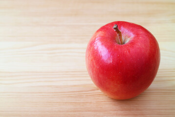 Closeup of a fresh ripe red apple isolated on wooden table