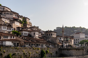 Mangalem Quarter in Berat, Albania. Characterized by traditional Ottoman-era houses featuring whitewashed facades and red-tiled roofs built into the hillside. Mosque with tall minaret on old town