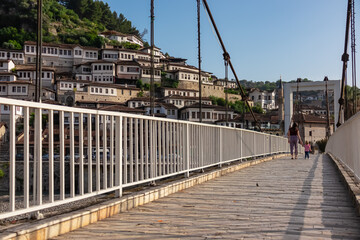 Mother with toddler walking on Gorica bridge in tourist town of Berat in Albania, Europe. Footbridge crosses river Osum. UNESCO World Heritage Site with Ottoman architecture. City of thousand windows