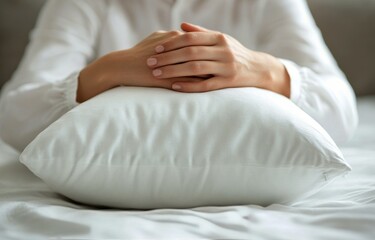 Calm hands resting on a white quilted pillow in a serene indoor setting during daytime