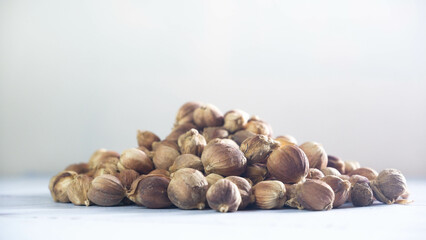 Close-up of dried cardamom pods, amomum kravanh, scattered on a white wooden surface, ideal for illustrating spice-related content, natural products, or culinary themes