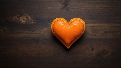 Obraz premium Heart-shaped orange on wooden surface representing love with a unique artistic style in warm tones.