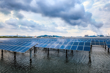 Solar panels and petrochemical plant industrial buildings and river landscape at sunset