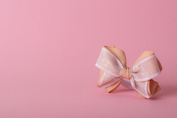 A beautiful bow made of turnip ribbon on a light pink background. copy space.