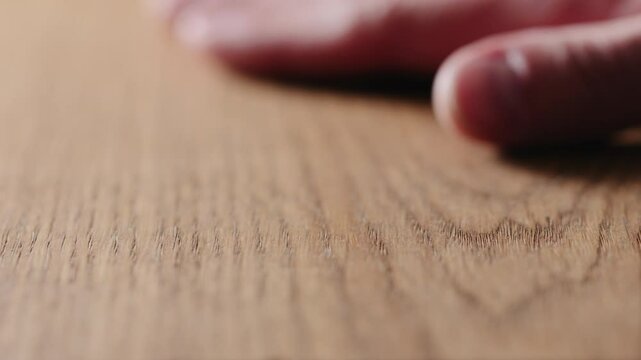 Slow motion man hand touch oil finished oak wood surface