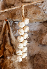 A bunch of white garlic bulbs hanging from a rope