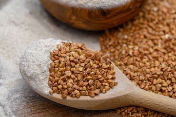 Palona Kasza gryczana w ziarnach na drewnianej łyżce obok mąki gryczanej