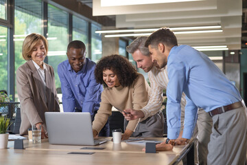 Successful businesspeople working in a coworking space working with laptop discussing strategy and business plan in modern office.