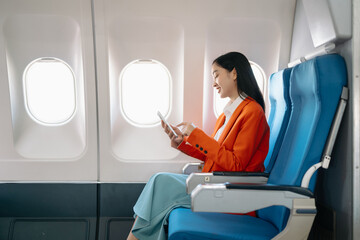 Asian executive excels in first class, multitasking with digital tablet, and smartphone. Travel in...
