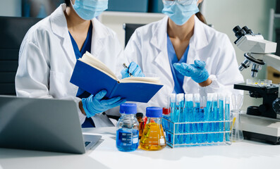 scientists in lab coats conducting research, handling glassware, and working with chemicals