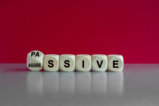 Turned a dice and changes the word passive to aggressive, or vice versa. Beautiful pink background. Business, psychological passive aggressive concept.