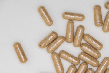 Brown herbal supplement capsules being poured from bottle