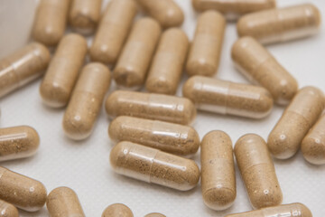 Brown pills spilling from bottle onto white surface