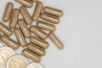 Brown pills lying next to euro coins symbolizing expensive healthcare costs