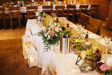 Rustic wooden wedding venue. Floral decorations festive atmosphere. Tables with food and drinks. Interior background. Celebrating and dining.