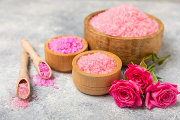 Sea salt for bath with aroma and rose flowers on textured wooden background. Pink sea salt. Spa treatments. Natural salt with herbs and essential oils. skincare concept. Meso for text. Copy space