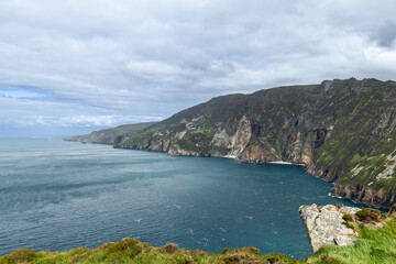 A view of the towering cliffs at Slieve League, Ireland, with steep rock faces and the vast Atlantic Ocean stretching into the distance