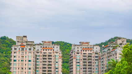 A top view of a residential area in Taipei, Taiwan that full of apartment buildings that are surrounded with trees and mountain. A symbol of good life, balance between city and nature