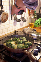 a man fries vegetables in a skillet on the stove