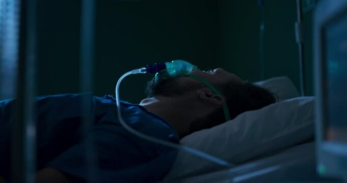 Young individual in hospital bed using oxygen mask.