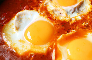 Closeup of eggs being poached in spiced tomato sauce for Shakshuka