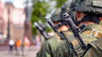 Brave soldier in camouflage uniform standing at attention with rifle on shoulder