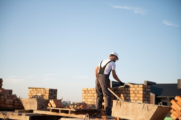 Man bricklayer installing bricks on construction site