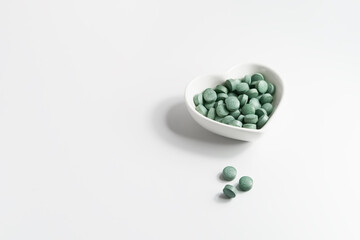 Green pills of chlorella and spirulina algae on a white table