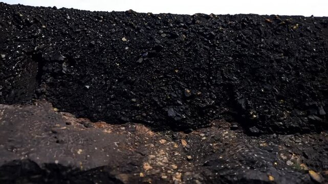 Geological section of soil, layers of coal and rock. Overburden open mine anthracite. Dark texture black color,  zoom in. slow motion. 4K video