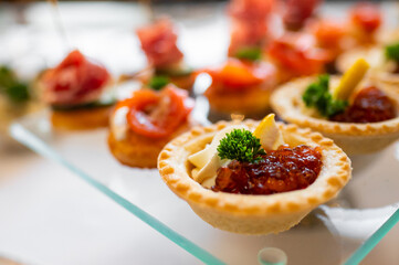 An assortment of elegantly presented canapés with various toppings, showcasing a variety of flavors and intricate presentation, perfect for catering events or gourmet gatherings
