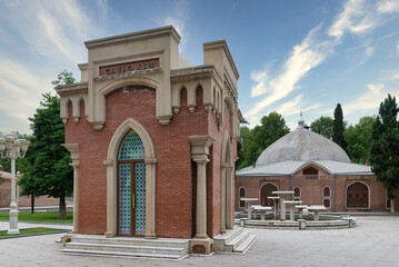 Obraz premium The Javad Khan Mausoleum stands elegantly with its distinct architecture, while the historic Juma Mosque looms beautifully in the background under a bright blue sky in Ganja city, Azerbaijan