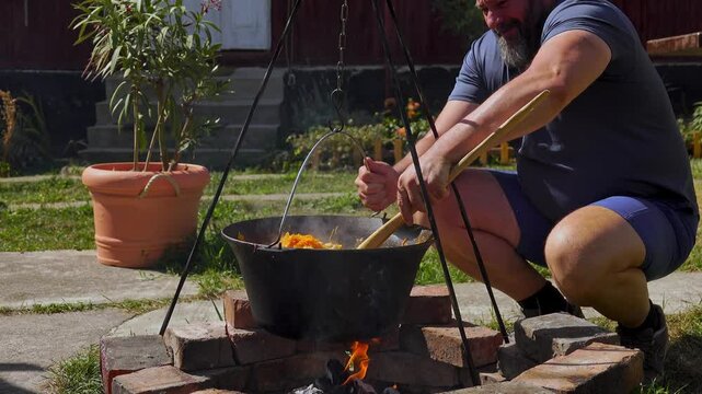 A traditional Romanian cooking scene showing onions being saut&eacute;ed in a cauldron over a wood fire, a key step in making authentic zacusca. The rustic outdoor setup highlights the time-honored methods