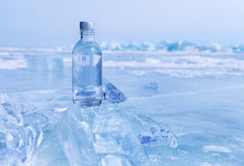 Glass bottle with cold natural drinking water stands on ice of frozen Baikal Lake on cold winter day. Advertising and branding of fresh ecological water. Nature ice background. Copy space, mock up