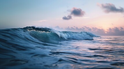A single wave breaking in the ocean at sunset.